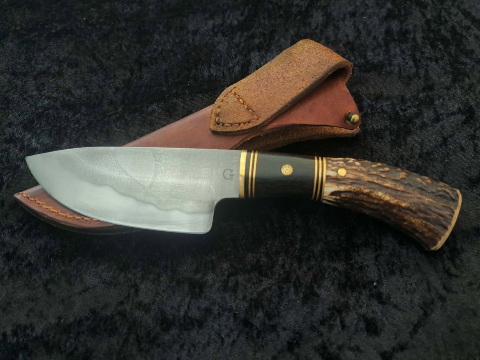 Couteau artisanal à manche en bois de cerf et laiton, posé sur son étui en cuir