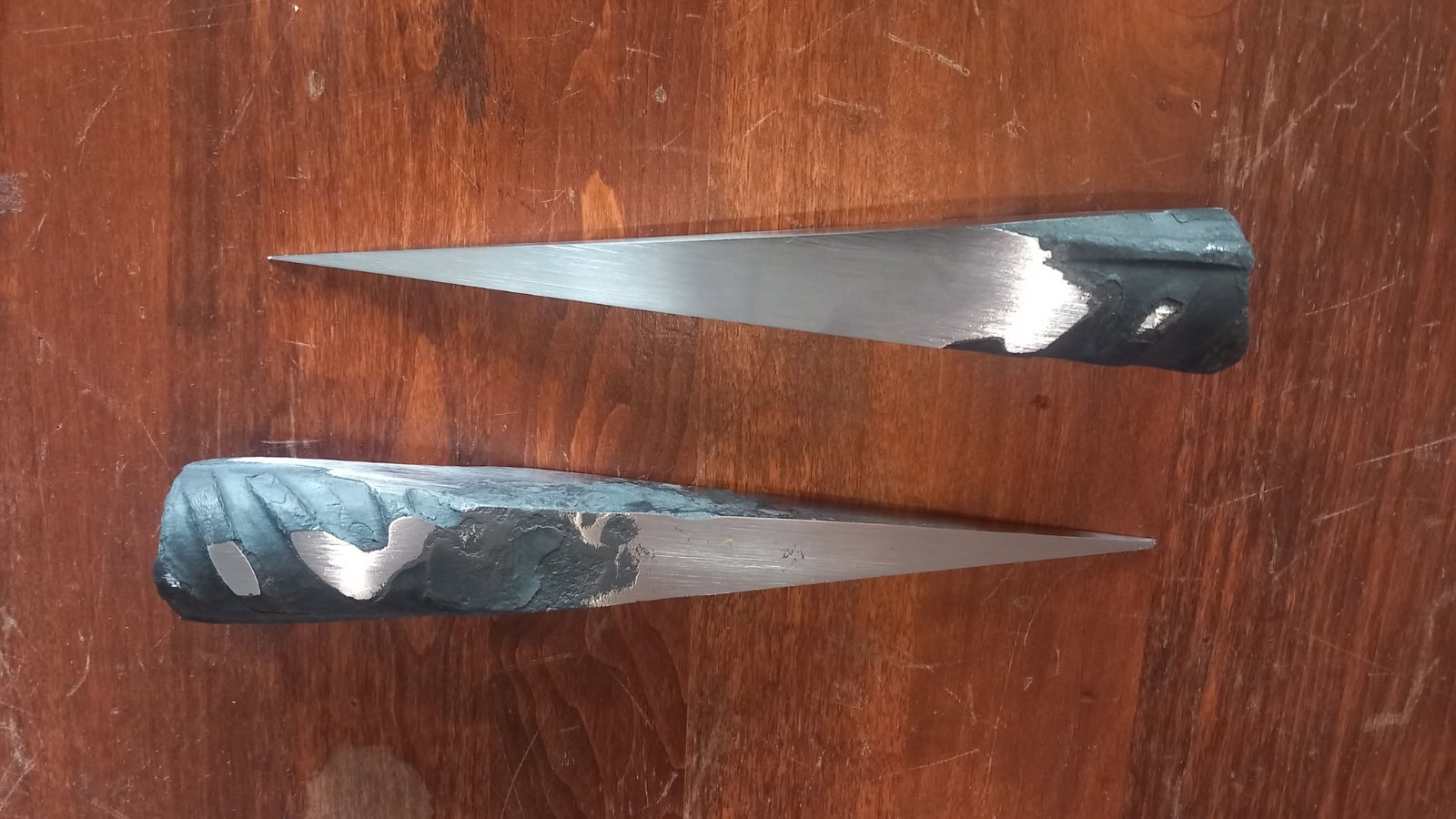Deux lames en cours de finition : brut de forge conservé et biseau poli