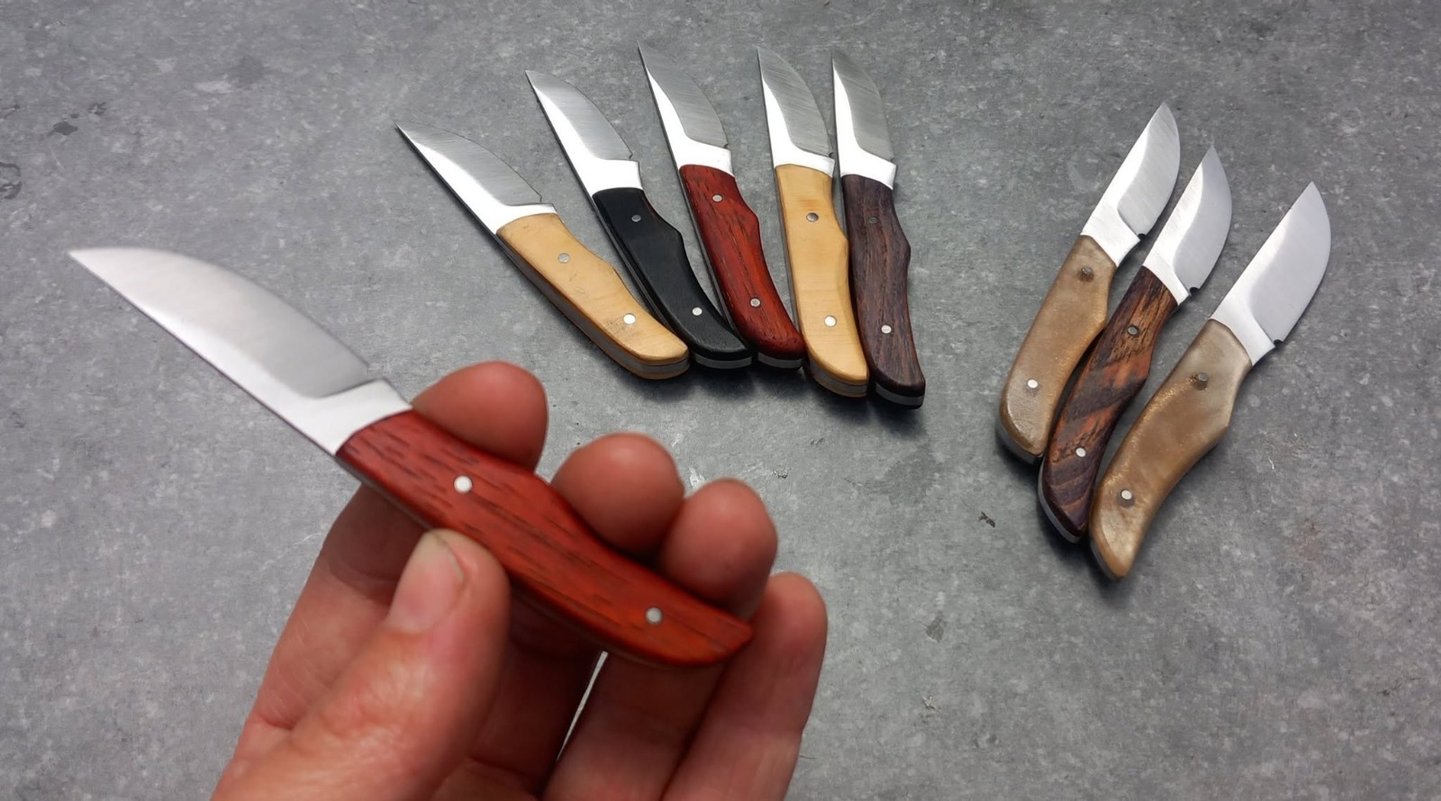 Couteau de poche artisanal tenu en main, manche en bois de rose