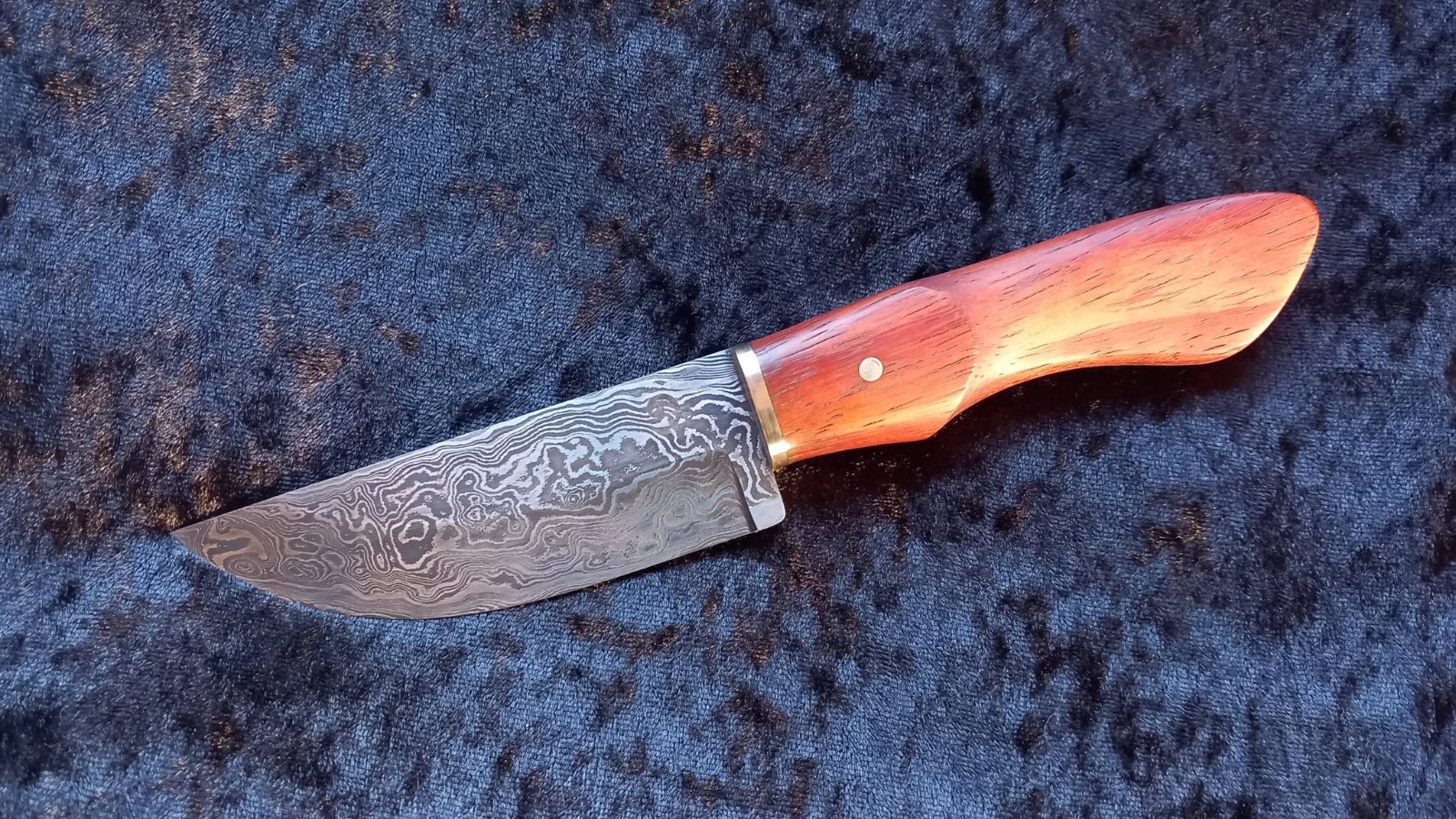 Motif de damas tourbillonnant sur la lame d'un couteau de chasse forgé à l'atelier