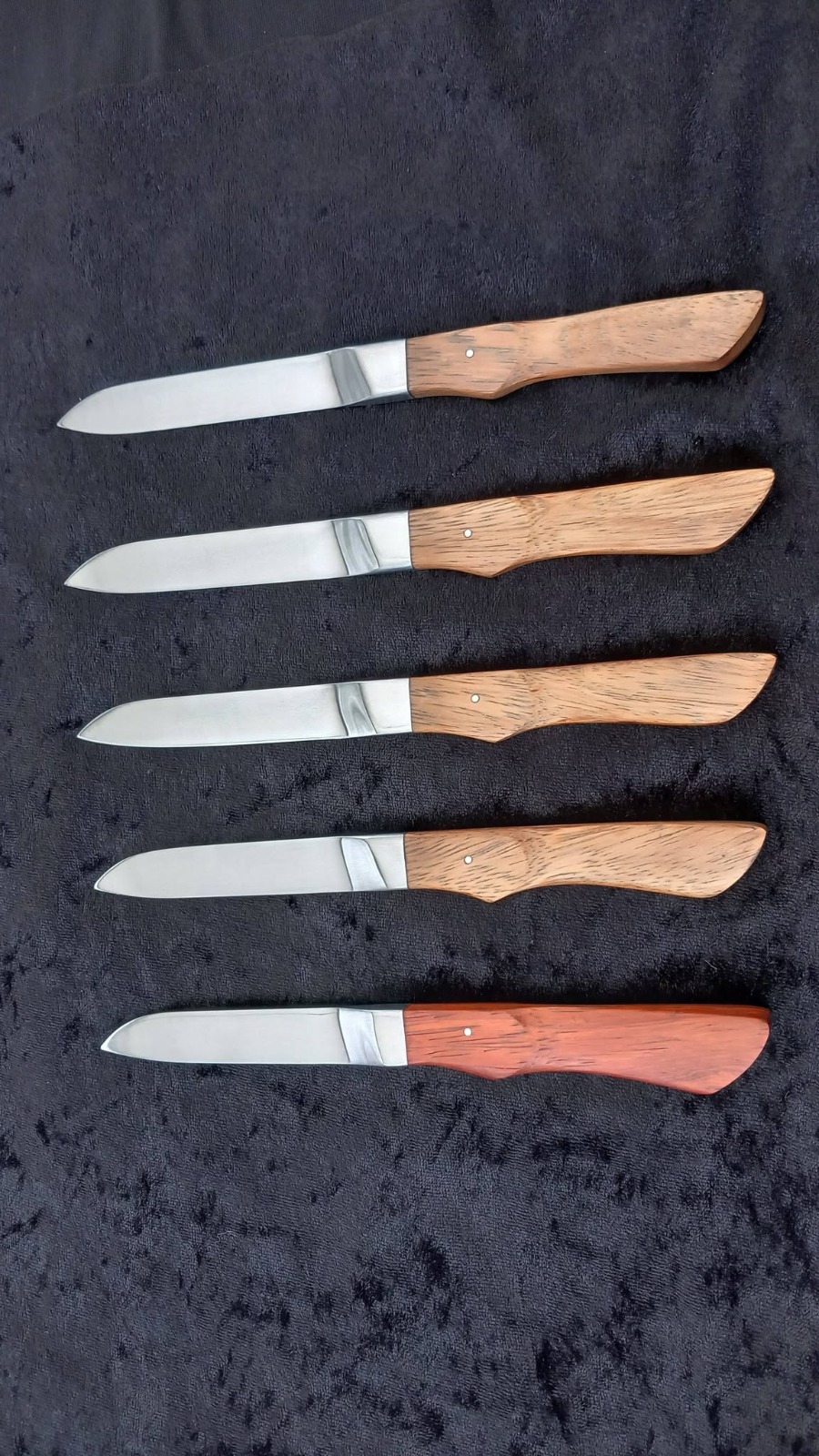 Cinq couteaux de table forgés main, lames polies et manches en bois massif